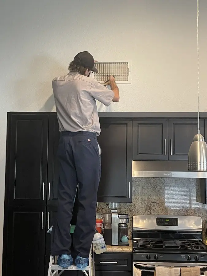 Technician inspecting an air vent during HVAC service in Home Gardens